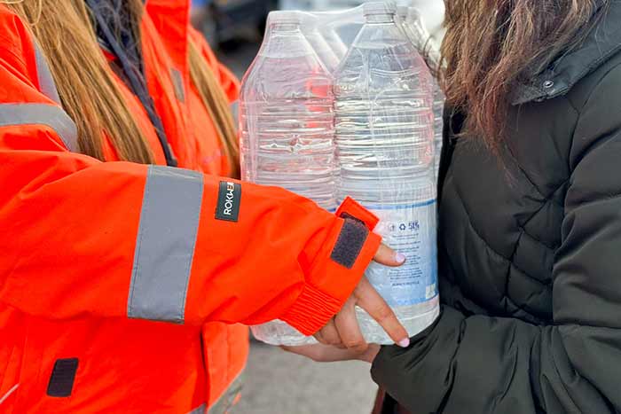person handing over bottled water